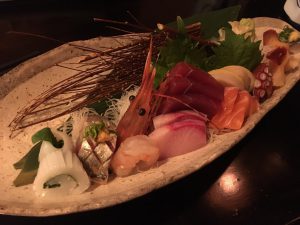 A beautifully styled platter of sashimi, featuring a large shrimp head
